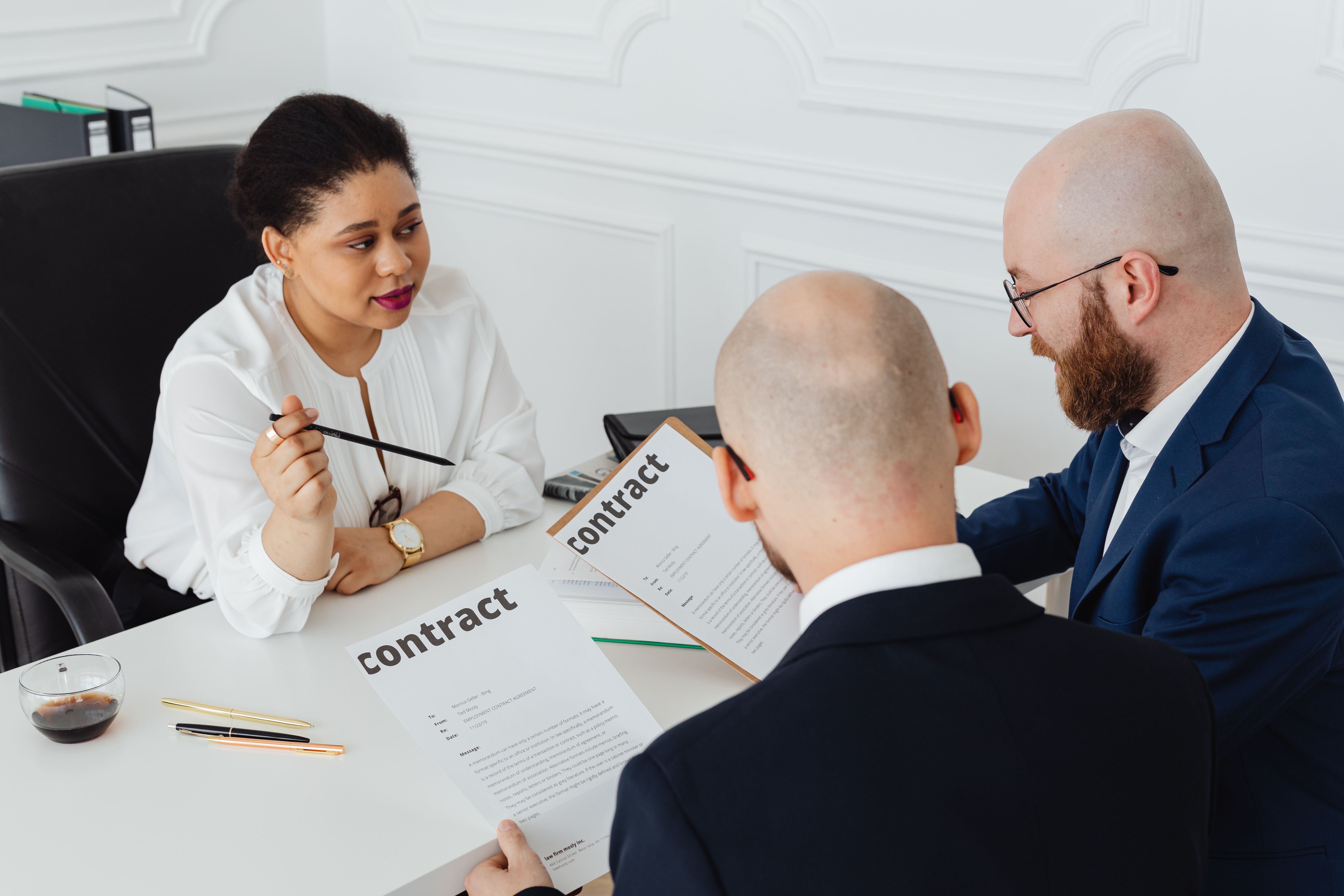 Three business professionals reviewing a contract in a boardroom negotiation