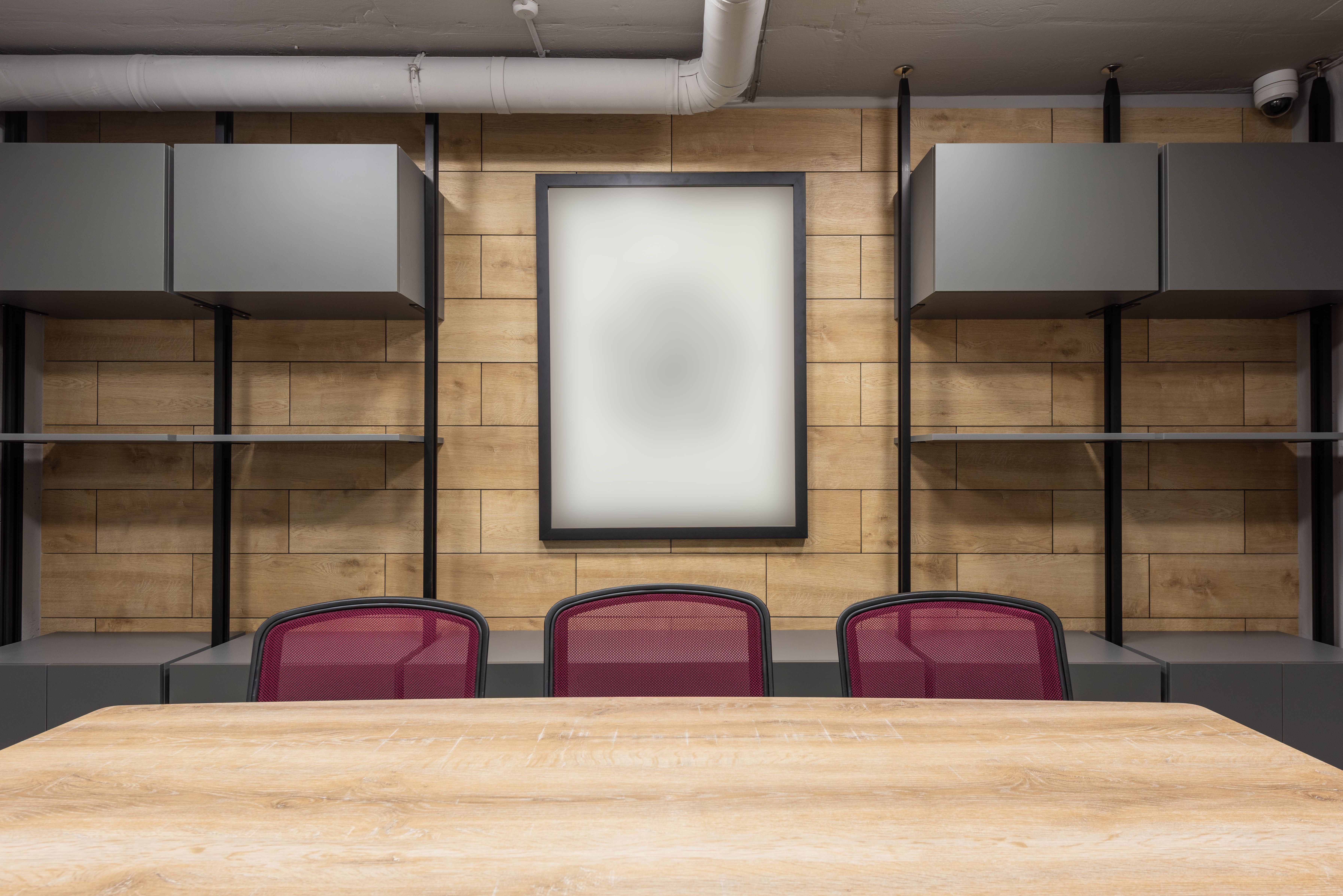 Empty modern boardroom with wooden table and chairs awaiting a company meeting