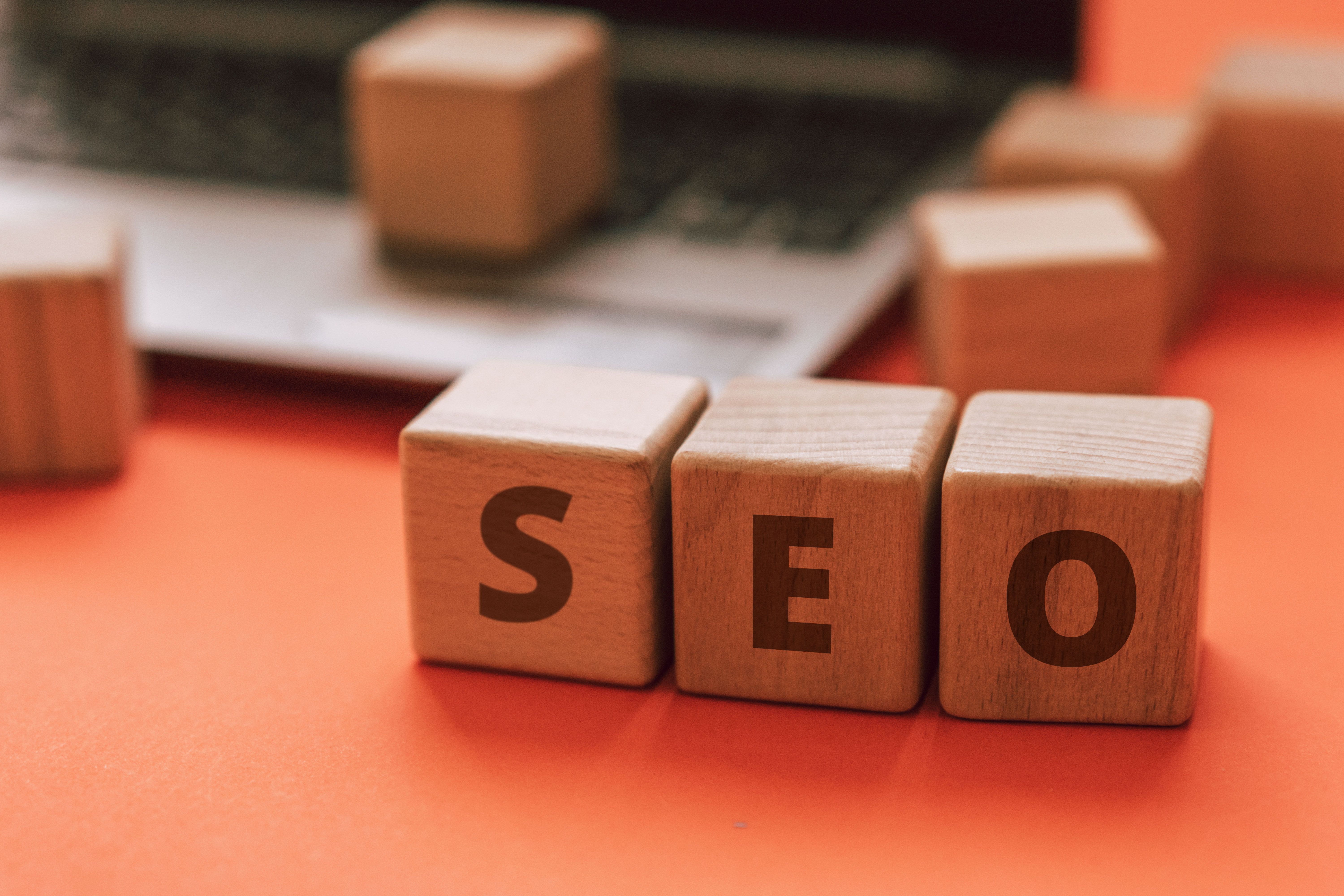 Wooden blocks spelling SEO on a laptop keyboard representing search optimization