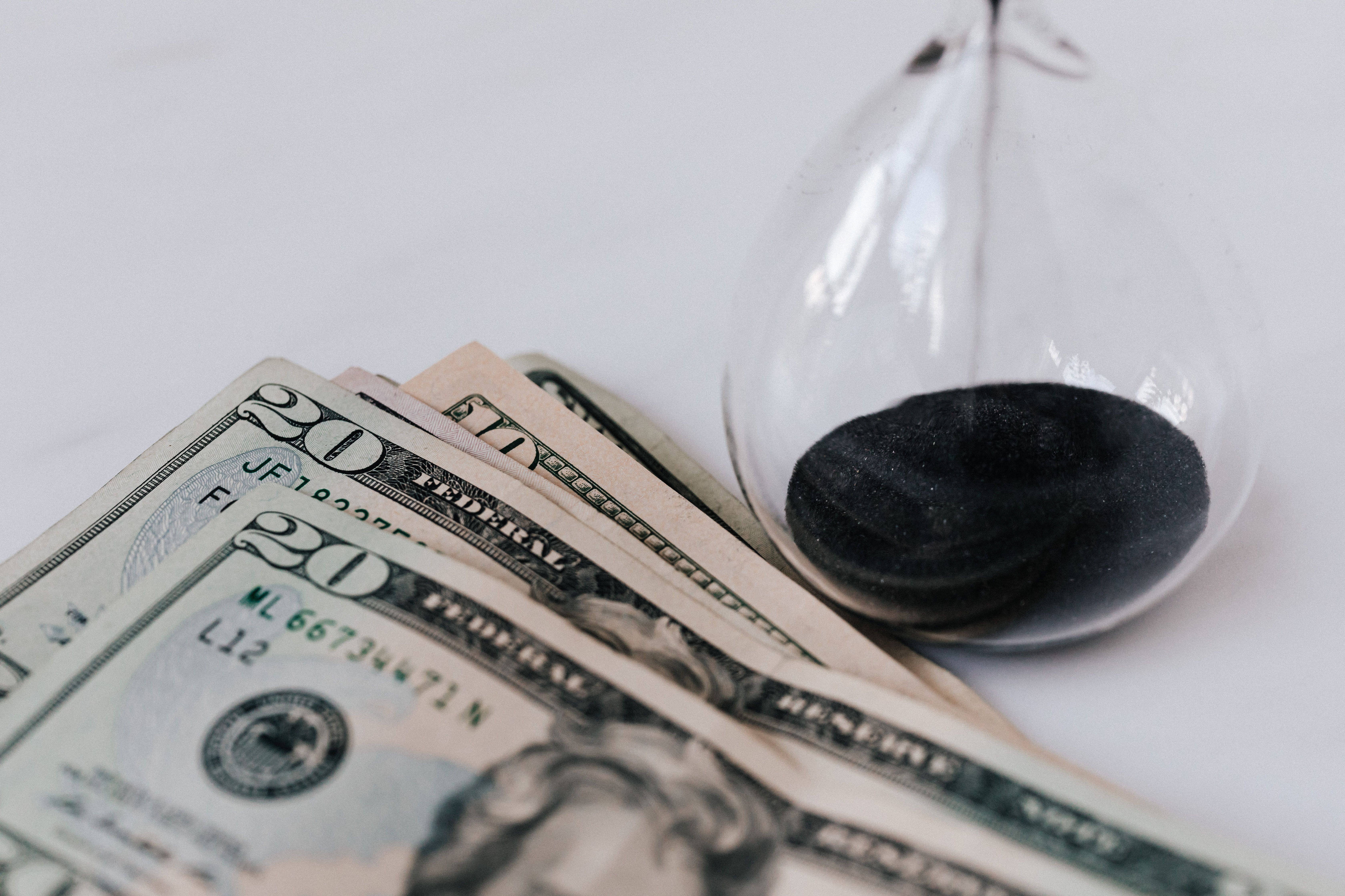 Hourglass beside banknotes illustrating billable hours and the rising cost of legal cases