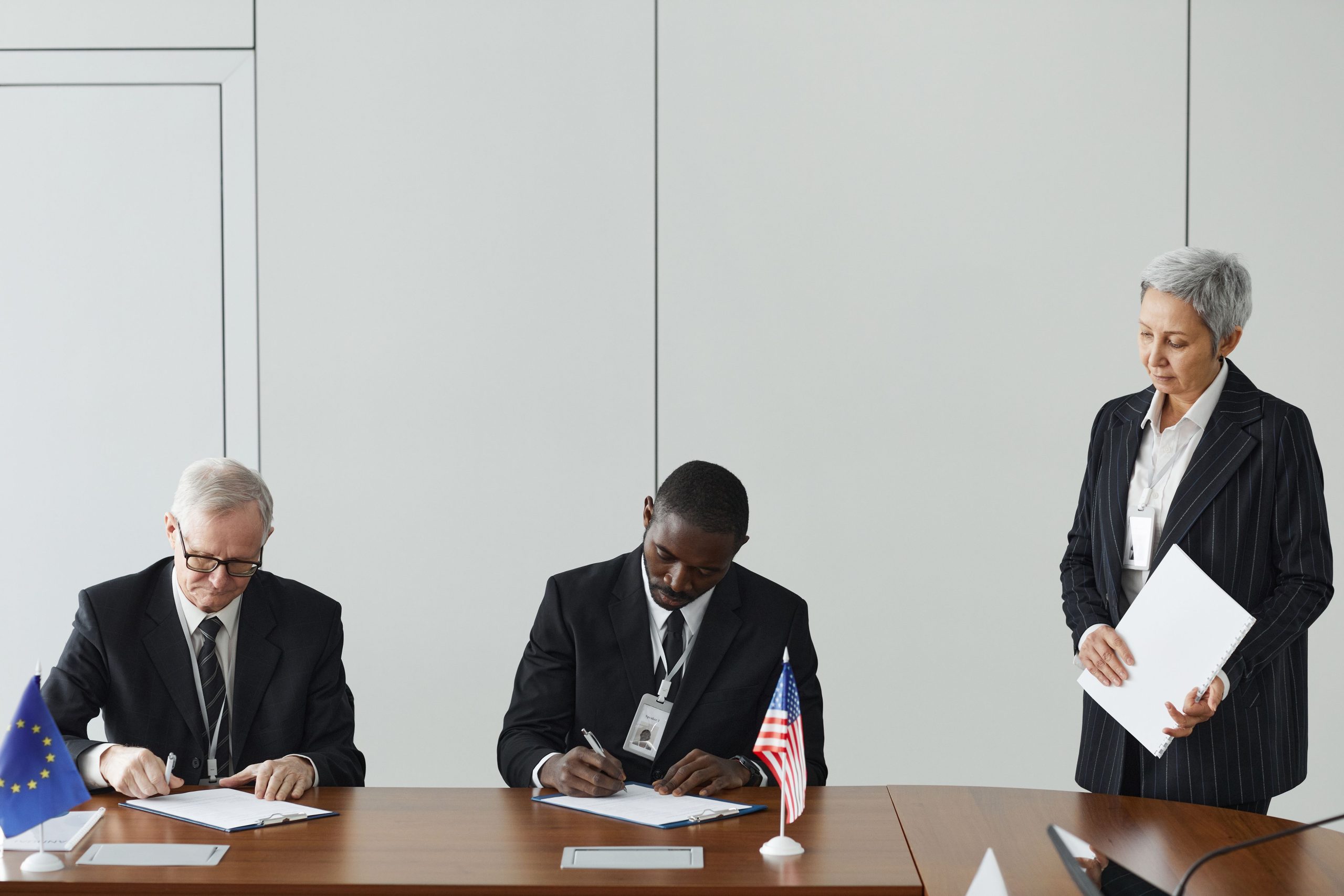 How International Relations Shape Business Confidence and Investment Executives signing an international agreement with EU and US flags on a wooden table
