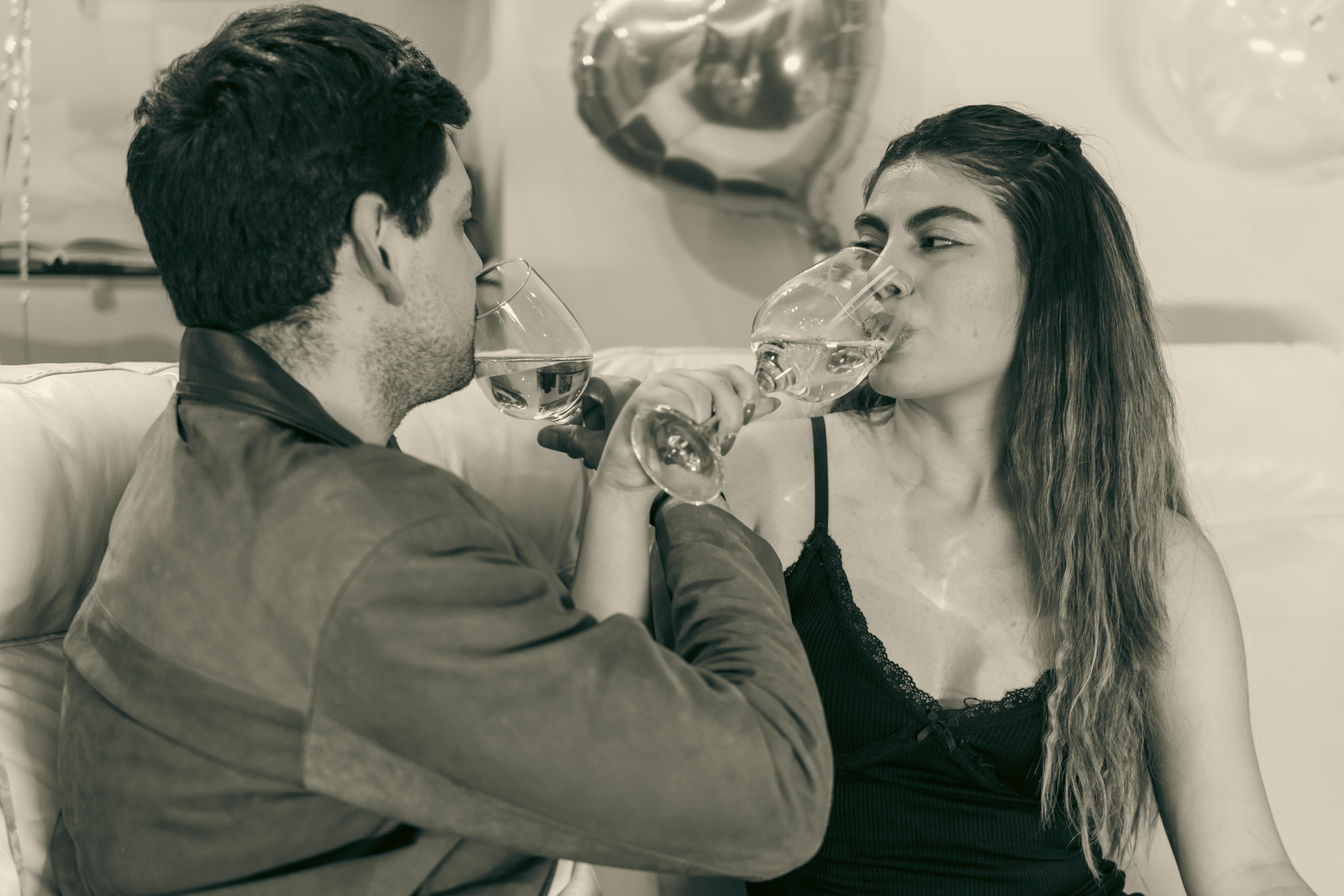 Couple toasting at home with heart decorations to keep the spark alive on a budget