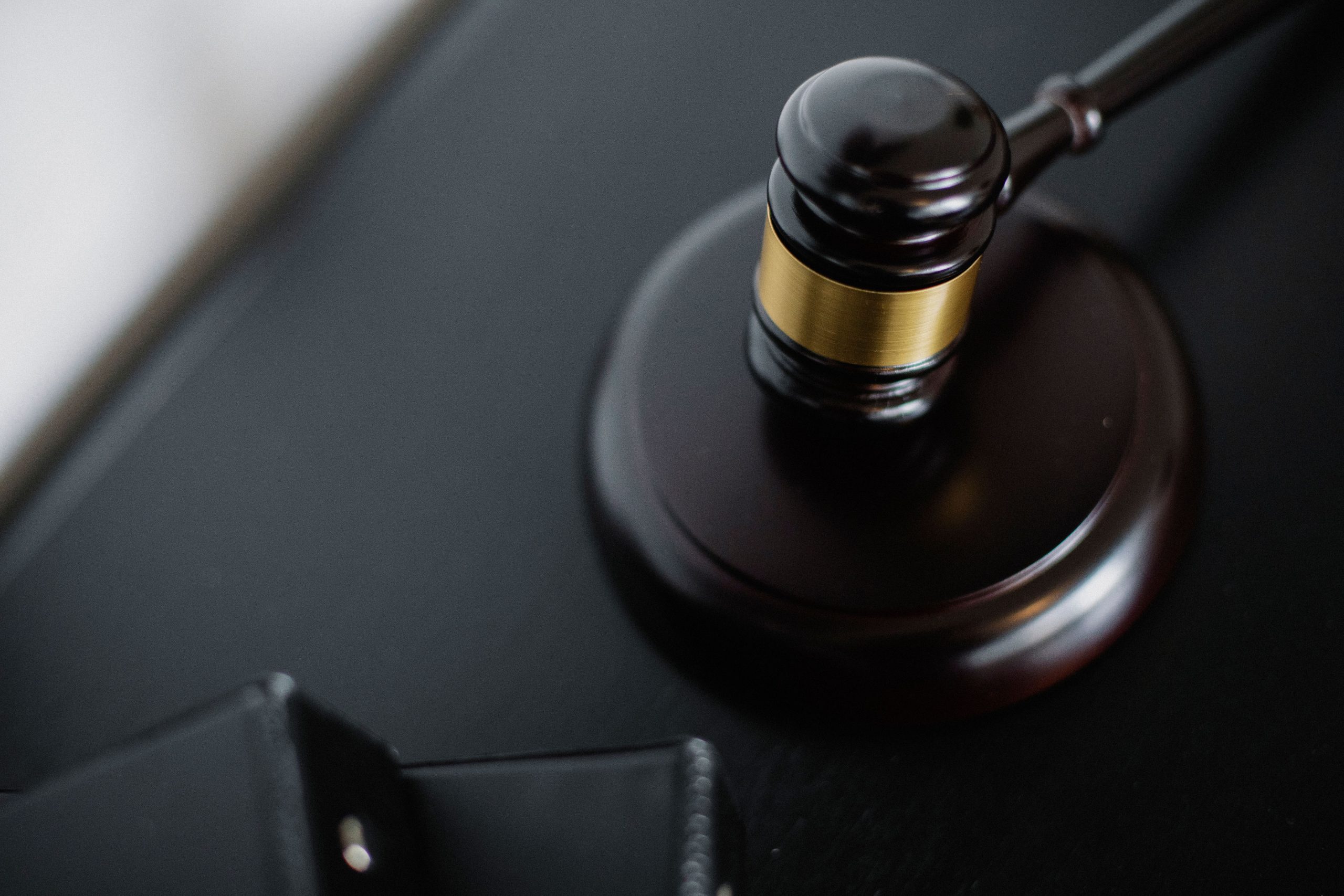 litigation-cost-courtroom-gavel-case-files Wooden gavel on a table beside case folders in a courtroom, symbolizing expensive litigation