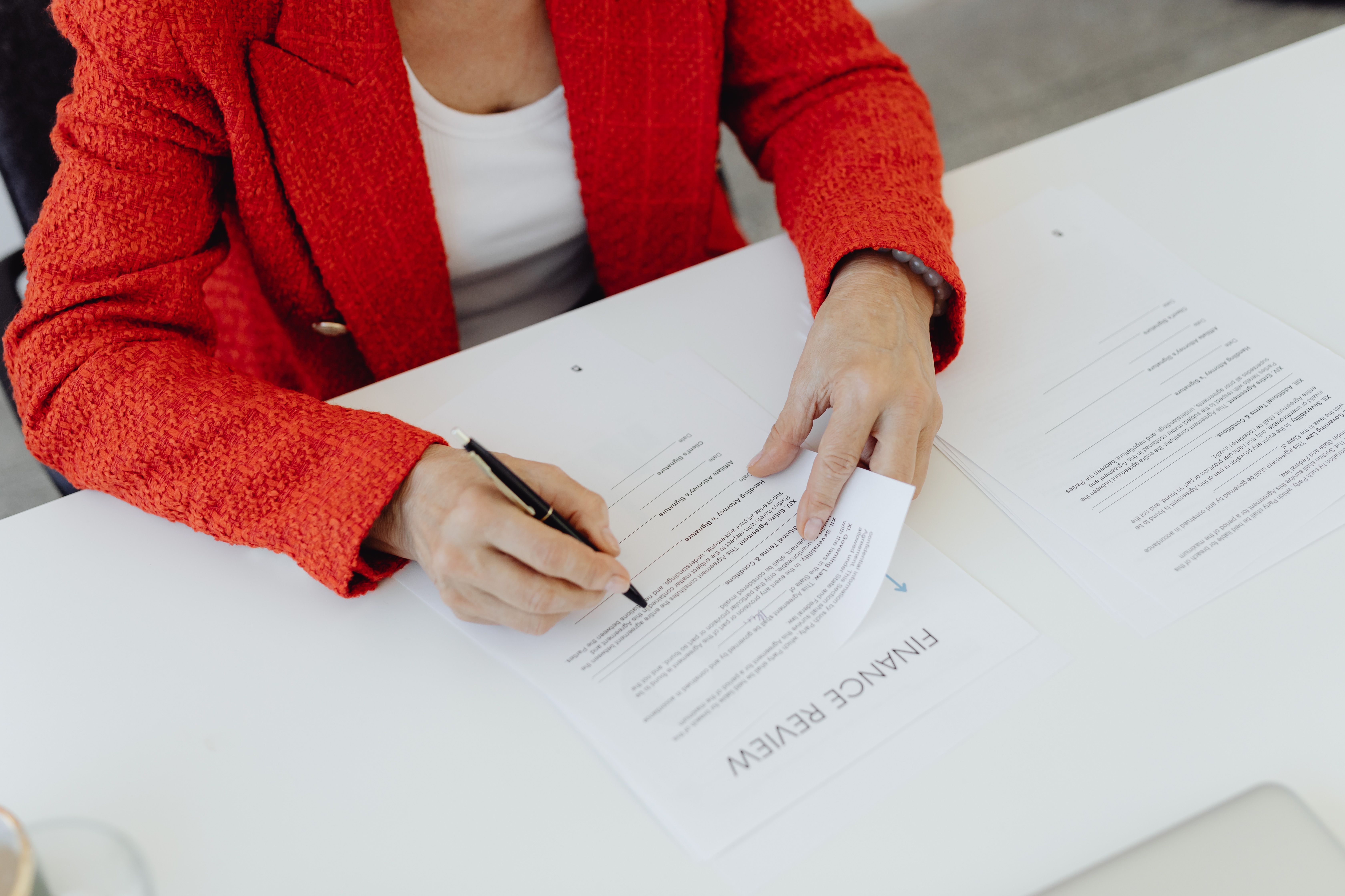 Businesswoman signing finance documents at an office desk