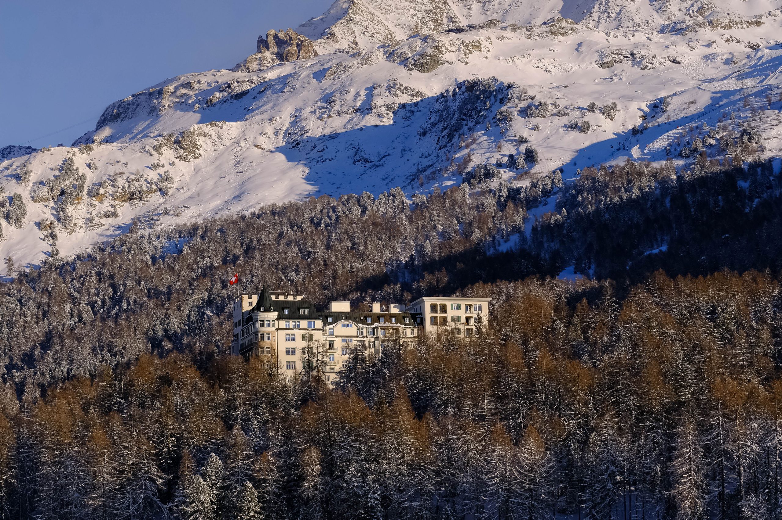 Luxury Spa Retreats in Bavaria and the Alps Worth the Splurge Luxury alpine hotel nestled among snow-covered mountains and a dense winter forest.