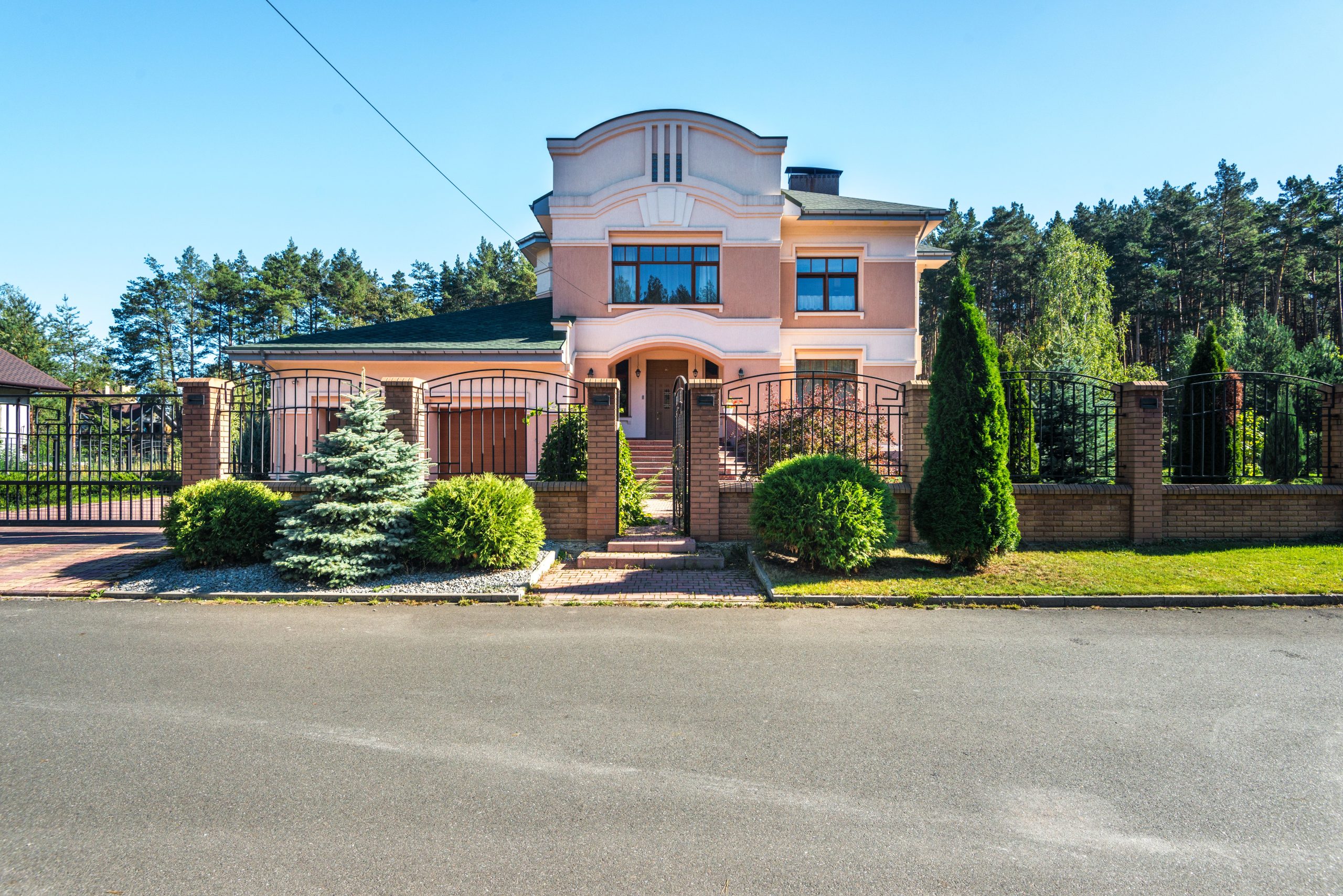 luxury-home-gated-security Luxury suburban home with landscaped garden and gated entrance, illustrating discreet residential security.