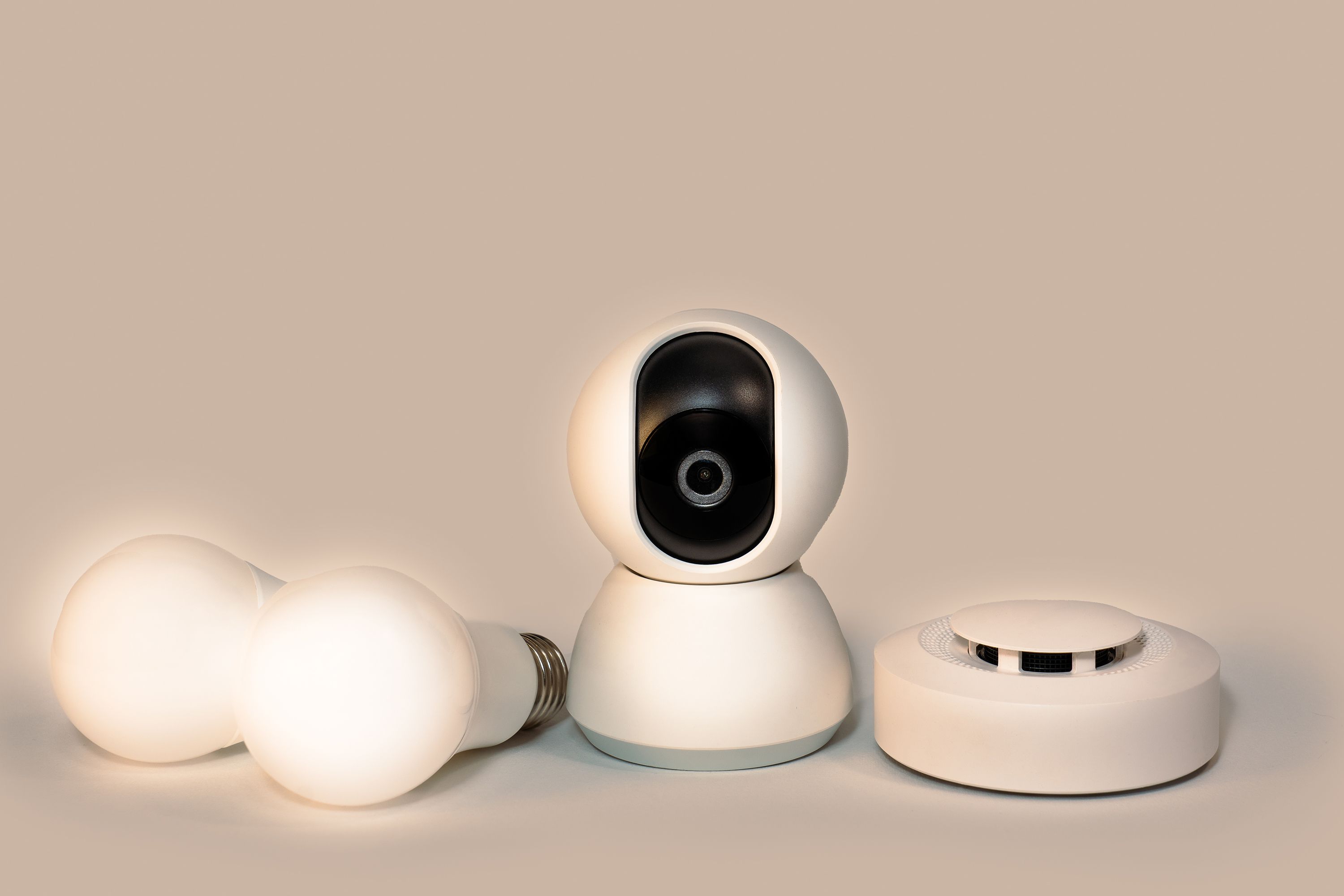Modern smart home gadgets including a CCTV camera, LED bulbs, and a smoke detector.