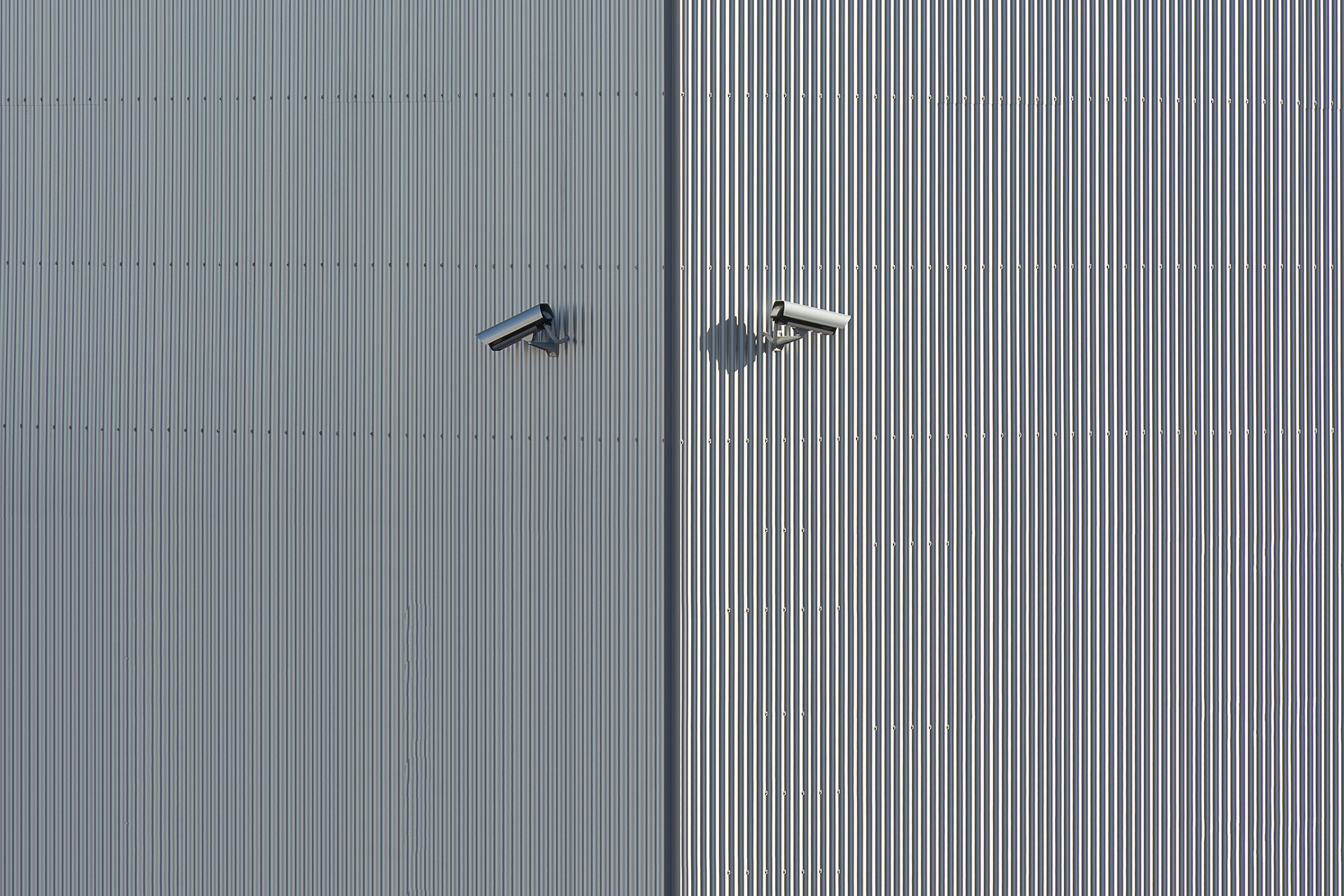 Two security cameras mounted on a minimalist exterior wall, illustrating unobtrusive monitoring.